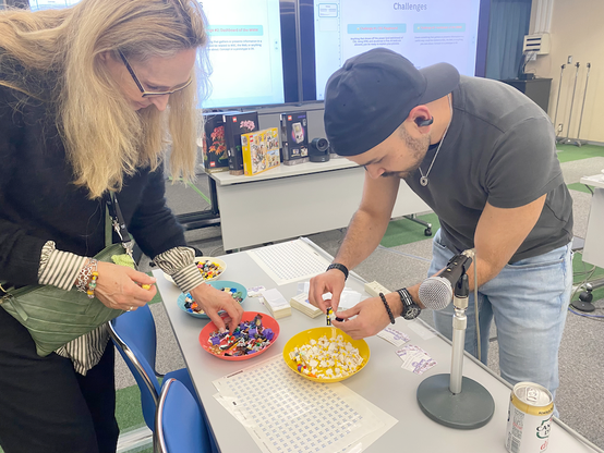 Two participants are building tiny mini figs with lego body parts